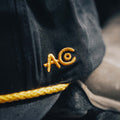 Close-up of the high-quality cotton/poly blend black fabric of the Skull & Roses Hat by Rural Cloth, featuring yellow embroidered letters 