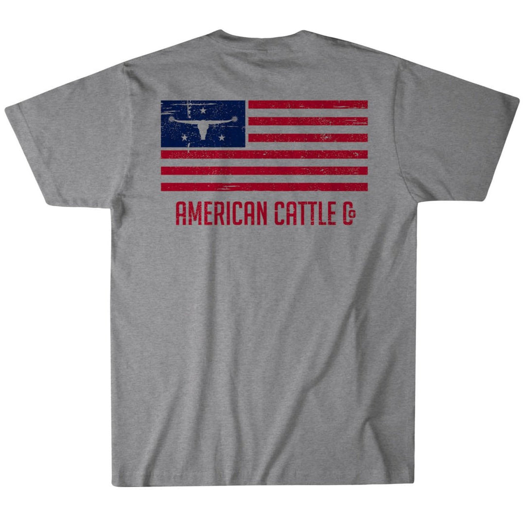 The AC Flag Tee by Rural Cloth features a stylized American flag with a Longhorn Graphic silhouette instead of stars, and "AMERICAN CATTLE CO" in red below. The distressed flag design captures the essence of American ranching spirit.