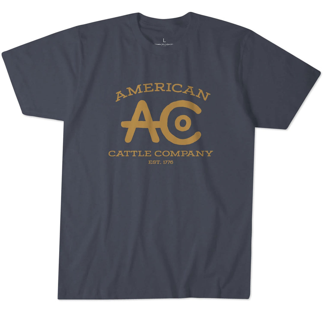 The ACC Brand Tee V2 from Rural Cloth is a premium-quality dark gray T-shirt featuring yellow text on the front that reads "American Cattle Company" above and below a large "AC" logo, with "Est. 1776" written underneath. Made from super soft combed ring-spun cotton, it comes with a round neck and short sleeves.