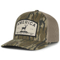 The America We Hunt Deer Hat - Bottomland by Rural Cloth is a camouflage baseball cap with a mesh back and snapback closure. It features a front patch that reads 