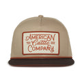 The Billboard Script Hat by 253408 is a beige and brown cap with a vintage patch reading 