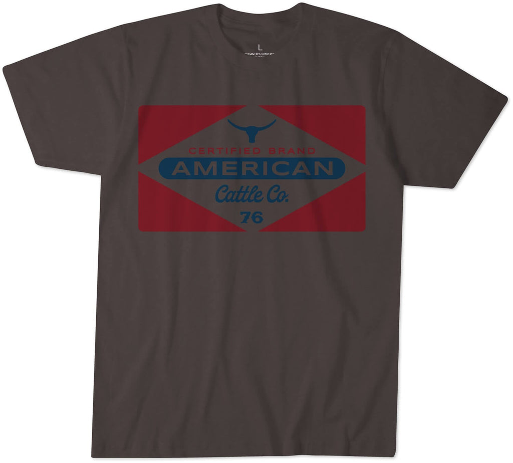 The Billboard Tee by Rural Cloth is a dark gray T-shirt made from super soft combed cotton. It features a large graphic on the front that includes a red diamond shape with a blue bull head at the top and the text 