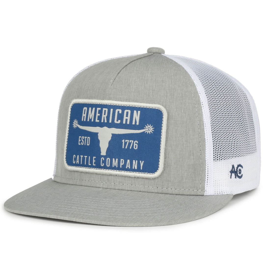 The Bull Spurs Hat-Flat from Rural Cloth is a light gray baseball cap with a white mesh back, featuring a rectangular blue patch on the front. The patch showcases a white longhorn steer logo and the text "AMERICAN CATTLE COMPANY ESTD 1776." The side of the cap is adorned with the initials "AC" in blue. This flat bill cap is ideal for cattle enthusiasts.