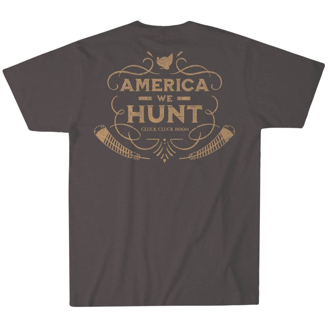 The Cluck Cluck Boom Tee by Rural Cloth is a super soft, dark-colored cotton T-shirt featuring a back graphic with "America We Hunt," a bird silhouette, two rifles, and the phrase "Cluck Cluck Boom" in vintage-style font. Proudly made in the USA.