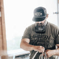 A bearded man is shown wearing a black Longhorn Hat and a t-shirt that both read 