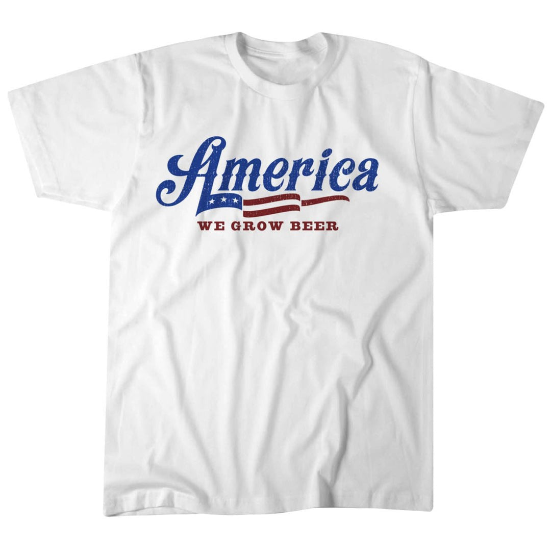 The Patriot Tee by Rural Cloth is a USA-made white T-shirt featuring "America" in blue with an American flag design and the phrase "We Grow Beer" in red. Crafted from ultra-soft cotton for premium comfort.