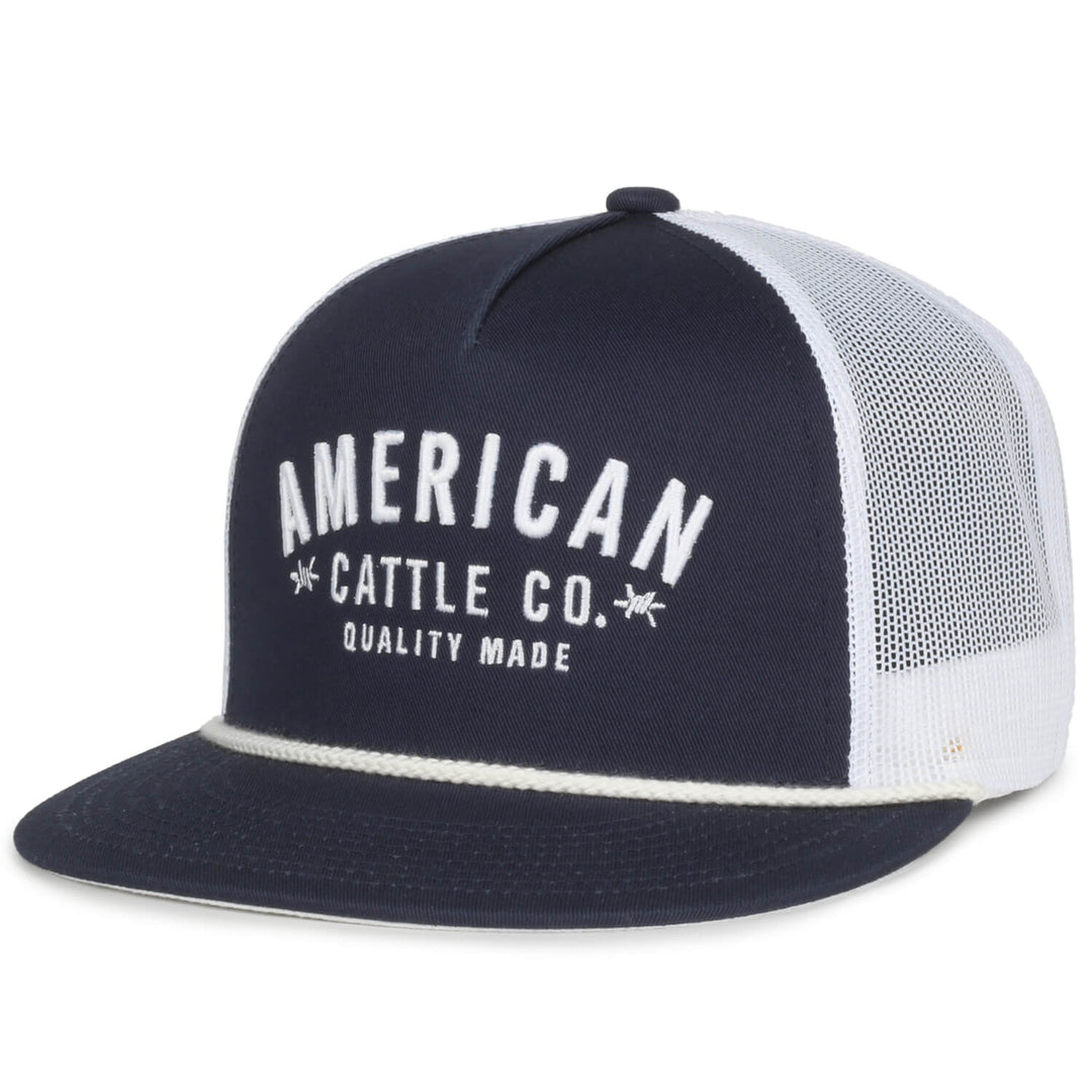 The Quality Made Hat by Rural Cloth is a dark blue and white mesh trucker hat with "American Cattle Co." and "Quality Made" embroidered in white on the front. It features a structured crown, a curved bill, and a convenient snapback closure for an adjustable fit.