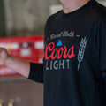 Wearing a black RC x CL Longsleeve shirt from Rural Cloth, emblazoned with the Coors Light logo alongside the 