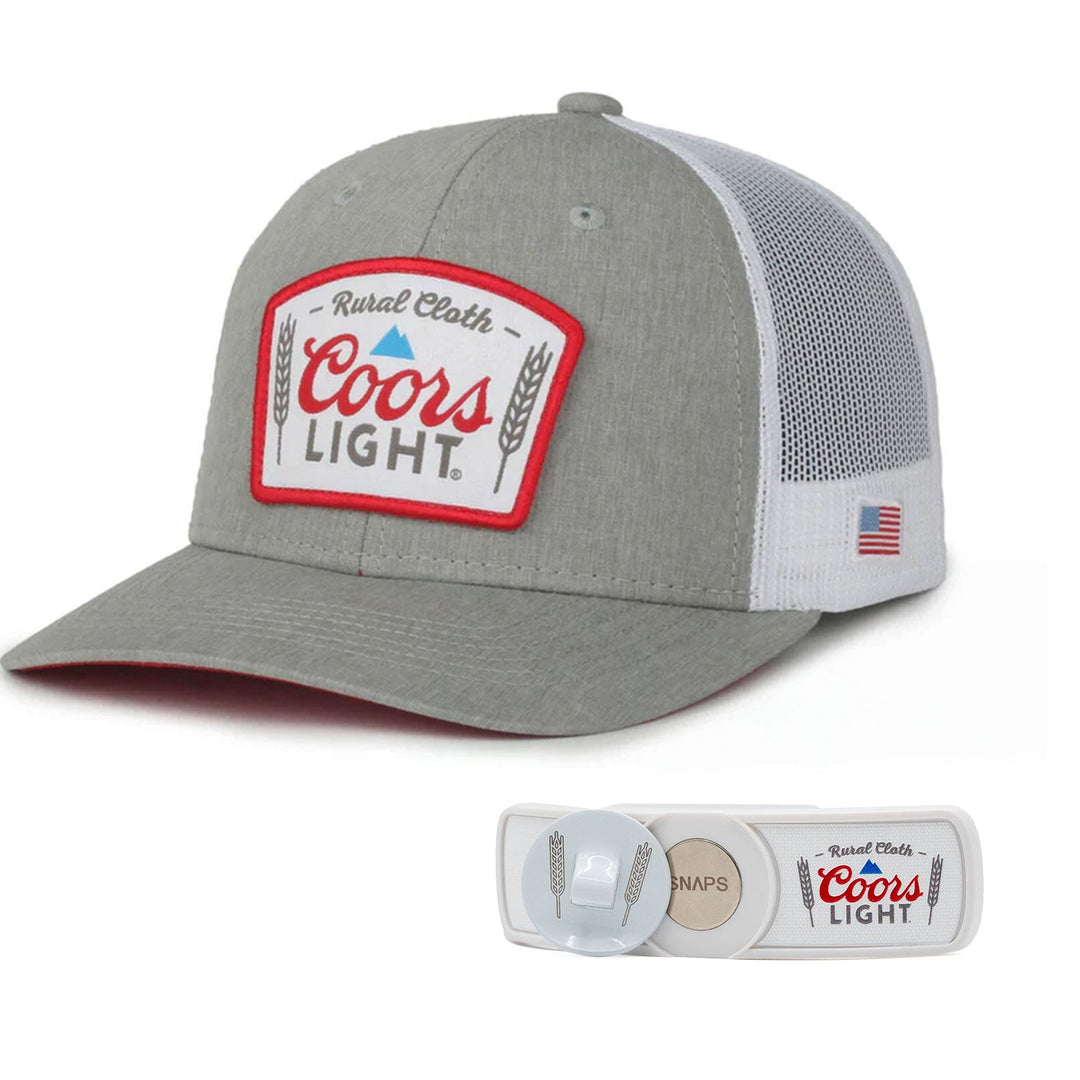 The RC x CL SNAPS Bundle from Rural Cloth includes a gray and white cap adorned with a "Coors Light®" patch on the front. The cap features mesh back panels and an American flag detail on the side. Alongside it is a SNAPS Bottle Opener keychain, showcasing a matching "Coors Light" design, making it an ideal set for any lover of this classic beverage.