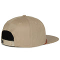 The Roper Hat by Rural Cloth is displayed from the back, showcasing its Western style. This tan baseball cap with a flat brim has an adjustable snapback closure and ventilation perforations. The fabric is plain, free of logos or designs.