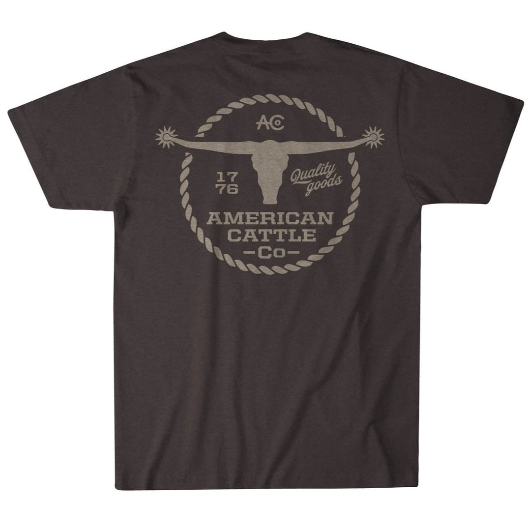 The Roper Tee by Rural Cloth is a vintage-inspired dark gray T-shirt featuring a large back graphic of a longhorn skull encircled by rope, with "1776," "American Cattle Co.," and "Quality goods" in beige, capturing timeless American heritage and style.