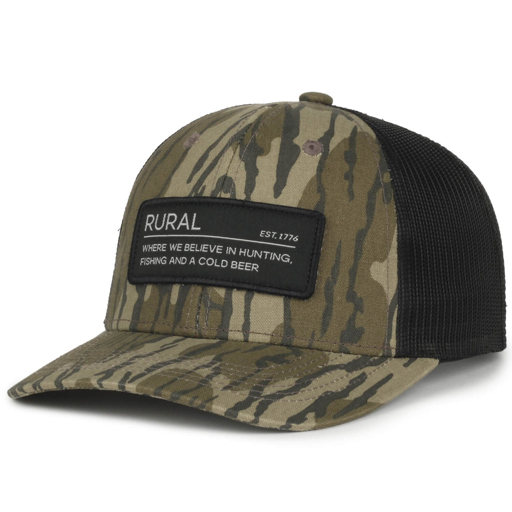 The Rural Cloth Rural Def Hat has a Mossy Oak Bottomland Camo front with a black mesh back. The patch states: 