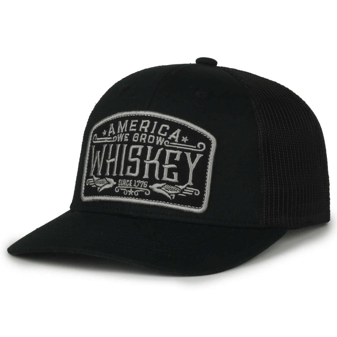 Check out the We Grow Whiskey Hat-Blackout by Rural Cloth, a stylish black trucker cap featuring a gray patch on the front with bold white letters that read "America One Grown Whiskey Since 1776." The back showcases a mesh design for breathability and a customizable fit. Shop now and enjoy free shipping!