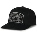 Check out the We Grow Whiskey Hat-Blackout by Rural Cloth, a stylish black trucker cap featuring a gray patch on the front with bold white letters that read 