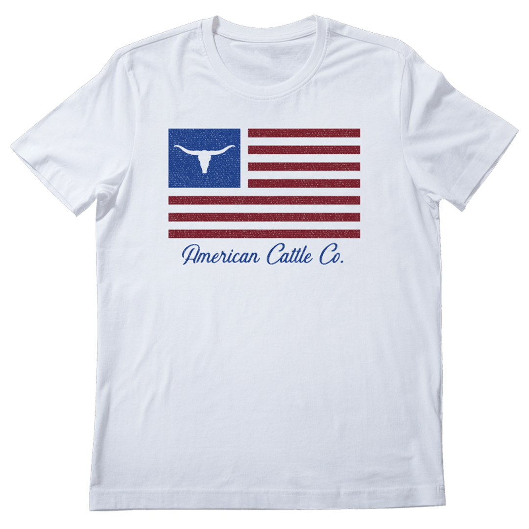 A white ACC Flag Tee by Rural Cloth featuring an American flag design, with a blue rectangle containing a white longhorn steer silhouette in the top left corner. Below the flag, "American Cattle Co." is written in blue cursive font, celebrating American cattle ranching.