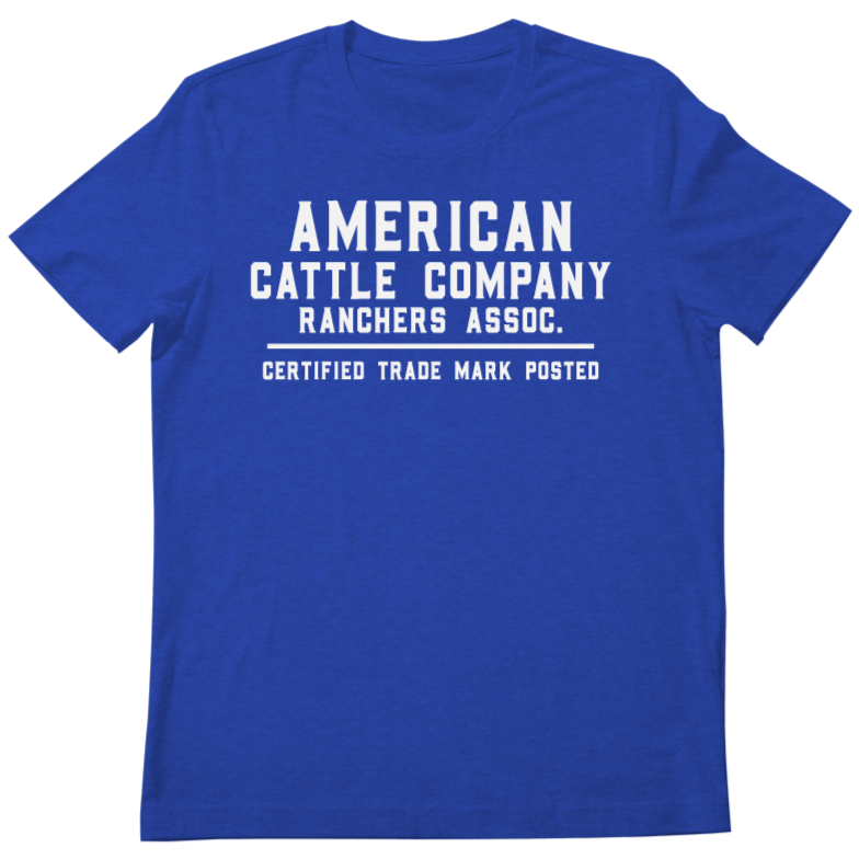 The Ranchers Association Tee from Rural Cloth features a blue T-shirt adorned with the Ranchers Association Logo and the text "American Cattle Company Ranchers Assoc. Certified Trade Mark Posted" printed in white on the front, making it perfect for showing your support for the ranching community.