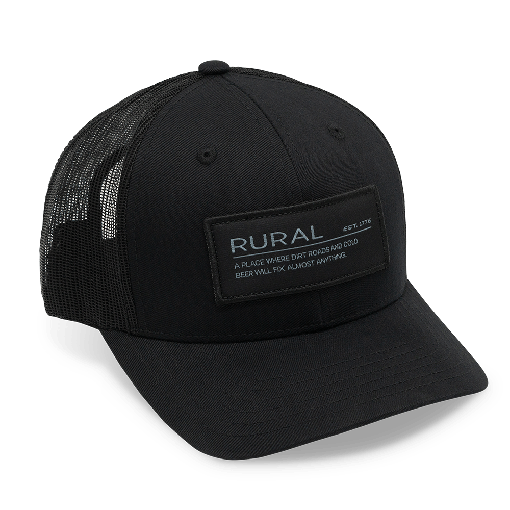 The Rural Def Hat by Rural Cloth is a black baseball cap featuring a breathable mesh back and an embroidered patch on the front. The patch reads, 