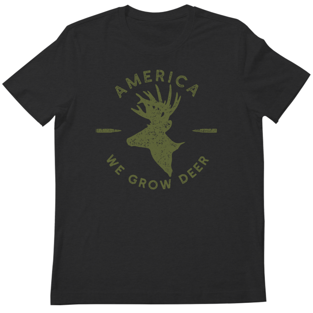 The We Grow Deer Tee-Black by Rural Cloth is a black T-shirt featuring an olive-green silhouette of a deer's head with large antlers in the center. Surrounding the deer’s head, the text "AMERICA WE GROW DEER" is displayed in a circle, with two horizontally placed bullets on either side, emphasizing wildlife conservation efforts.
